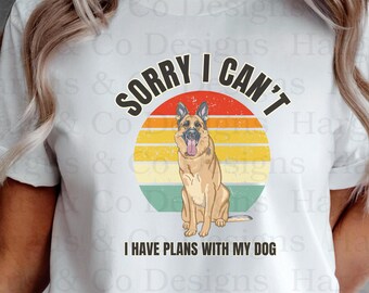 May include: White t-shirt with a vintage-style graphic of a German Shepherd dog sitting in front of a sunset. The text "Sorry I Can't I Have Plans With My Dog" is printed on the shirt.