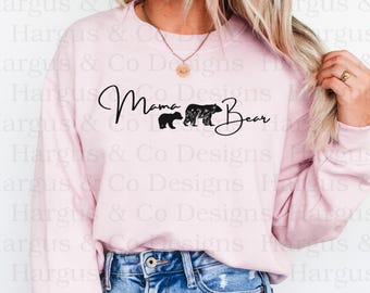 May include: A pink sweatshirt with the text "Mama Bear" in black cursive lettering. Two black bear silhouettes are below the text, one larger than the other.