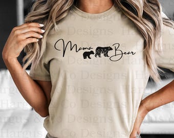 May include: A tan t-shirt with the text "Mama Bear" in black script. Two black bear silhouettes are walking behind the text, one larger than the other.