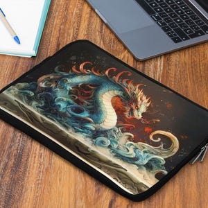 May include: Black laptop sleeve featuring a detailed illustration of a blue and red dragon amidst swirling water. The dragon has intricate scales and a fierce expression. The sleeve is on a wooden surface.