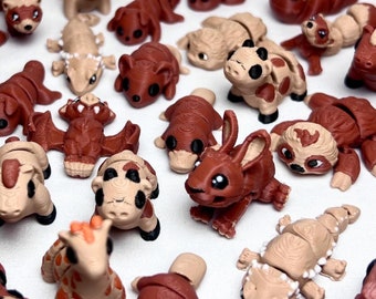 May include: A collection of small, brown and tan animal figurines. The figurines are made of a soft, pliable material and are designed to be bendable. The figurines include a variety of animals, such as a giraffe, a platypus, a sloth, a hippopotamus, and a rabbit.