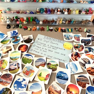 May include: A display of colorful, handmade miniature figurines on shelves, with a variety of creatures and characters. Below, a collection of circular background cutouts with landscape illustrations and a handwritten note with instructions.