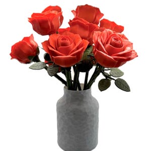 May include: A bouquet of bright orange roses in a gray textured vase. The roses are arranged in a cluster with their stems extending out of the vase.