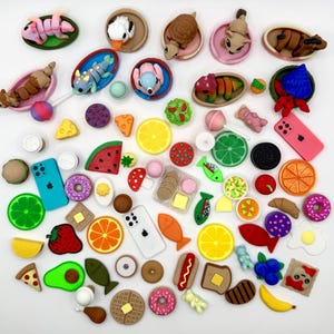 May include: A collection of colorful, miniature food and object charms. Includes a variety of items such as a slice of pizza, a donut, a phone, a slice of watermelon, and a hamburger. The charms are in various colors and shapes, perfect for crafting or jewelry making.