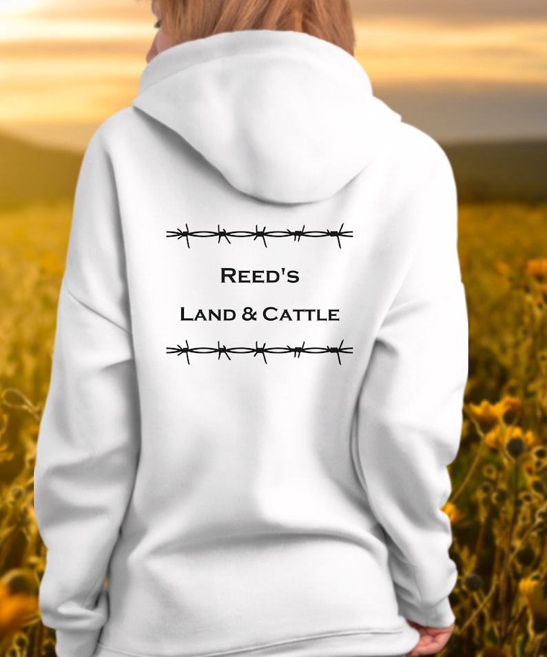 Puede incluir: Sudadera con capucha blanca con texto negro que dice "REED'S LAND & CATTLE" con gr&aacute;ficos de alambre de p&uacute;as arriba y abajo del texto.