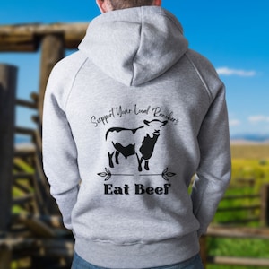 May include: A gray hooded sweatshirt with a black silhouette of a cow and the text "Support Your Local Ranchers Eat Beef" printed on the back.