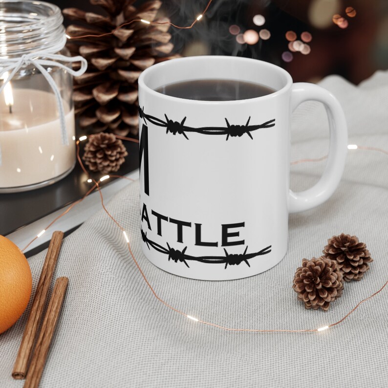 Puede incluir: Taza de cer&aacute;mica blanca con texto negro y dise&ntilde;o de alambre de p&uacute;as que dice "I'm Seattle". La taza est&aacute; llena de caf&eacute; y sale vapor de la parte superior.