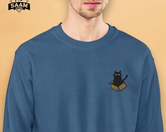 Op de afbeelding: Een donkerblauw sweatshirt met een geborduurde zwarte kat die in een doos zit op de linkerborst. De kat heeft gele ogen.