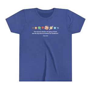 Op de afbeelding: Een blauw t-shirt met een afbeelding van de planeten in ons zonnestelsel en de tekst "De hemel verkondigt de heerlijkheid van God, en het uitspansel vertelt van zijn handwerk." Psalm 19:1