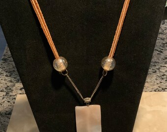 GORGEOUS champagne rectangular, wavy and glass pendant. Strung on silver chain, soft leather suede and two champagne colored glass beads!