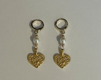 May include: A pair of gold hoop earrings with a dangling pearl and a filigree heart charm.