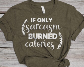 Puede incluir: Camiseta verde oliva con la frase "IF ONLY sarcasm BURNED calories" en blanco. Diseños florales blancos enmarcan el texto. La camiseta es de material suave y de estilo casual.