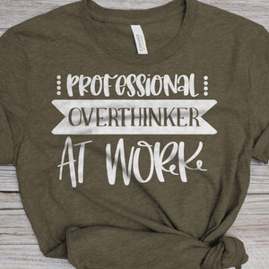 May include: A green t-shirt with the text "Professional Overthinker At Work" in white lettering.