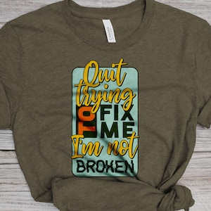 May include: A green t-shirt with the text "Quit trying to fix me I'm not broken" in a colorful box.