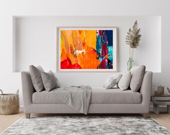 May include: A gray couch with pillows and a throw blanket in front of a framed abstract painting with orange, red, blue, and yellow paint strokes.