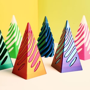 May include: Six colorful, geometric Christmas tree ornaments in various shades of green, blue, pink, and red. The ornaments are made of a smooth, glossy material and have a unique, abstract design.