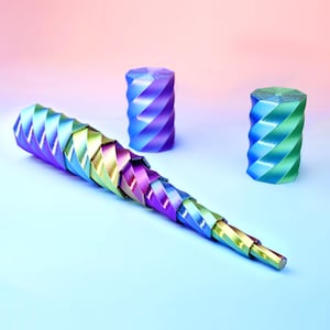 May include: A collapsible, multi-segmented, tapered wand featuring a spiral, twisted design with a metallic, iridescent finish that shifts between shades of blue, purple, green, and gold. Two separate, cylindrical, spiral-textured caps are included.