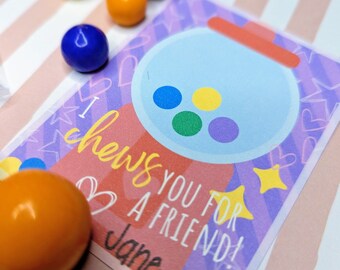 Może przedstawiać: Kartka z życzeniami z motywem automatu do gumy i żółtym napisem "I chews you for a friend!". Karta ma fioletowo-czerwone tło z sercami i gwiazdami. Kilka kolorowych gum do żucia jest rozrzuconych wokół karty.