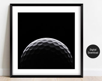 Op de afbeelding: Een zwart-witfoto van een golfbal, waarbij alleen de bovenste helft van de bal zichtbaar is. De achtergrond is zwart.