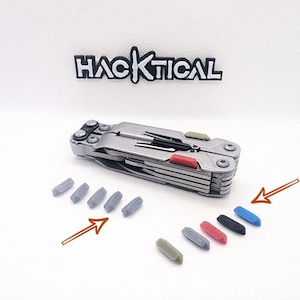 Puede incluir: Una multiherramienta plateada con varios accesorios y detalles de color. También se incluyen varias piezas de repuesto grises y de colores. La palabra "HACKTICAL" está encima de la herramienta. La herramienta incluye un cuchillo, un destornillador y unos alicates.
