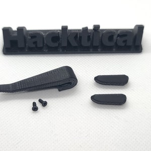 Puede incluir: Un conjunto de piezas impresas en 3D de color negro para un proyecto Hacktical. El conjunto incluye una pinza, dos piezas peque&ntilde;as y dos tornillos.