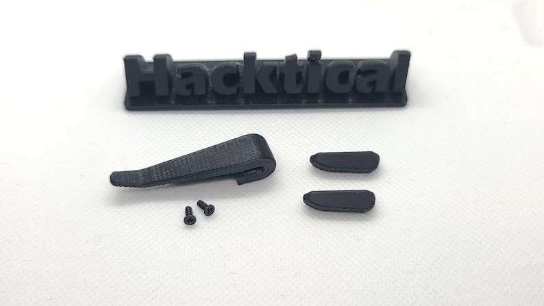 Puede incluir: Un conjunto de piezas impresas en 3D de color negro para un proyecto Hacktical. El conjunto incluye una pinza, dos piezas peque&ntilde;as y dos tornillos.