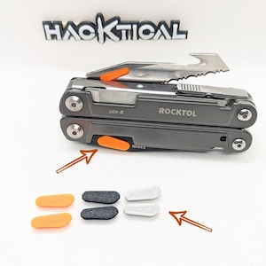May include: A gray multi-tool with orange and black accents. The multi-tool is open and the blade is visible. The multi-tool has the text "ROCKTOL" and "GEN-R" on it. There are three replacement parts for the multi-tool: two orange, one black, and two gray.