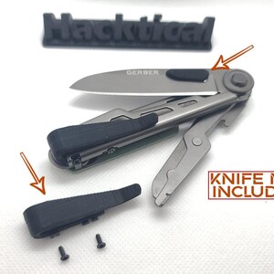 Puede incluir: Un conjunto de tres piezas de pl&aacute;stico negro para una multiherramienta Gerber. Las piezas son un mango, un clip y un tornillo peque&ntilde;o. El texto "KNIFE NOT INCLUDED" est&aacute; impreso sobre un fondo blanco.