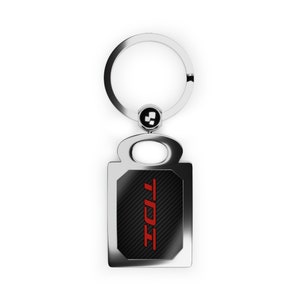 May include: A silver key chain with a black and red rectangular tag. The tag has a carbon fiber pattern and the word "TODT" in red letters.