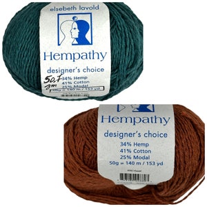 May include: Two skeins of yarn, one teal green and one brown. The yarn is labeled "Hempathy designer's choice" and lists the fiber content as 34% hemp, 41% cotton, and 25% modal. The teal skein is 50.7 grams and 140 meters, while the brown skein is 50 grams and 140 meters.