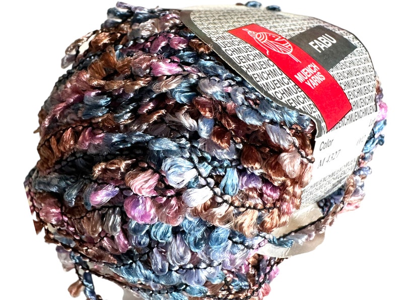 May include: A ball of multi-colored yarn with a brown, blue, pink, and white color scheme. The yarn is labeled "FABU" and "MUENCH YARNS" with the color number "M4327".