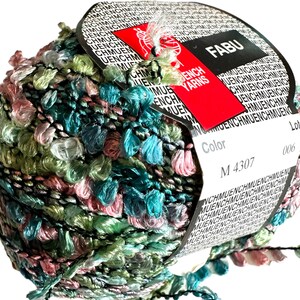 May include: A ball of green, pink, and blue yarn with a black thread running through it. The yarn has a fuzzy texture and is wrapped around a white label with the text "FABU" and "ENCH YARNS" in red. The label also has the text "Color M 4307" and "Lot 006".