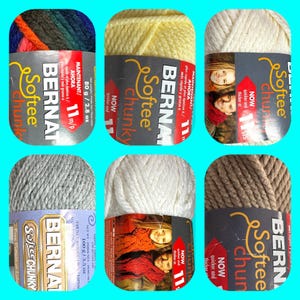 May include: Six skeins of Bernat Softee Chunky yarn in various colors, including gray, white, beige, yellow, and a multi-colored skein. Each skein has a label with the Bernat logo and the text "Softee Chunky" and "Now quicker and thicker".