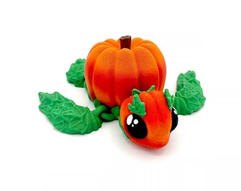 May include: A small, orange pumpkin-shaped turtle figurine with green leaves and black eyes.