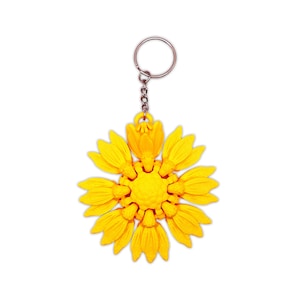 May include: A yellow sunflower-shaped keychain with a silver metal ring and chain.