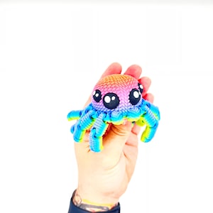 Op de afbeelding: Een regenboogkleurig gehaakt octopus speelgoed met grote zwarte ogen.