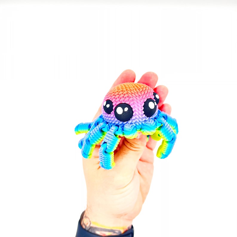 Op de afbeelding: Een regenboogkleurig gehaakt octopus speelgoed met grote zwarte ogen.