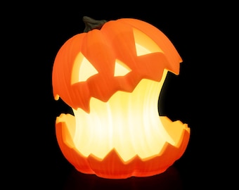 May include: An illuminated orange pumpkin with carved eyes and a mouth, emitting a warm yellow glow. The Halloween decoration is set against a black background, creating a spooky ambiance.
