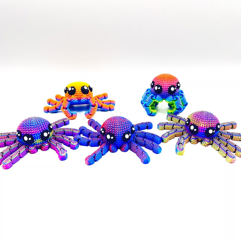 Op de afbeelding: Vijf kleine gebreide octopus speelgoed in verschillende regenboogkleuren. Elke octopus heeft grote zwarte ogen en een textuur, iriserende afwerking.