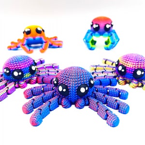 Op de afbeelding: Vijf kleurrijke gehaakte spinnen speelgoed. De spinnen zijn gemaakt met een verscheidenheid aan kleuren, waaronder roze, blauw, oranje en geel. De spinnen hebben grote, zwarte ogen en acht poten.