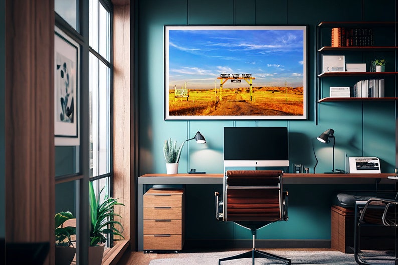 May include: A teal blue home office with a desk, a computer, a chair, and a framed landscape photograph of a wooden gate with the text "Circle View Ranch" above it.