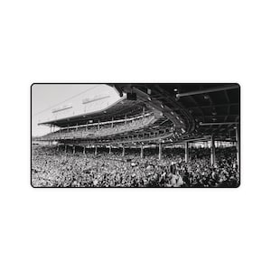 May include: A black and white photograph of a large crowd of people in a stadium. The stadium has multiple levels of seating and a large, open roof.