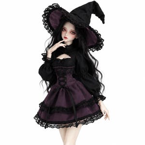 Peut inclure: Une poupée articulée aux longs cheveux noirs, portant un chapeau de sorcière noir avec une bordure en dentelle, un haut noir à manches longues avec une encolure découpée et une jupe violet foncé avec des volants en dentelle noire.
