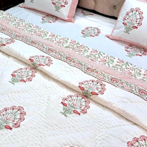 Boho floral cotton quilt in blush pink and sage green spread across queen size bed