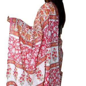 May include: A white and pink cotton saree with a floral print. The saree has a red border with a white and orange floral design.