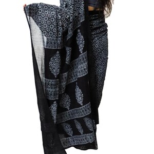 May include: A black and white cotton saree with a paisley print. The saree is draped over a person's body.