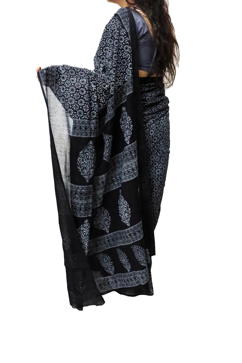 May include: A black and white cotton saree with a paisley print. The saree is draped over a person's body.