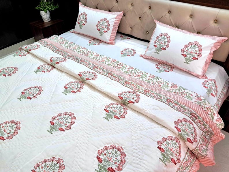 Boho floral cotton quilt in blush pink and sage green spread across queen size bed