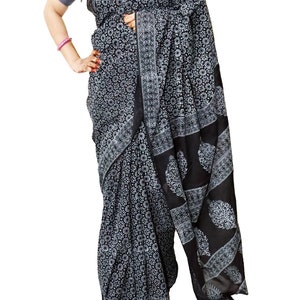 May include: A black and white cotton saree with a floral print. The saree is draped on a person and has a border with a paisley design.