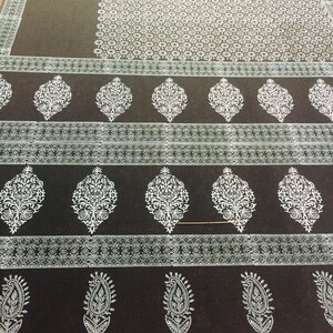 May include: A black fabric with a white floral pattern. The fabric has a repeating pattern of small white flowers and larger white floral designs.